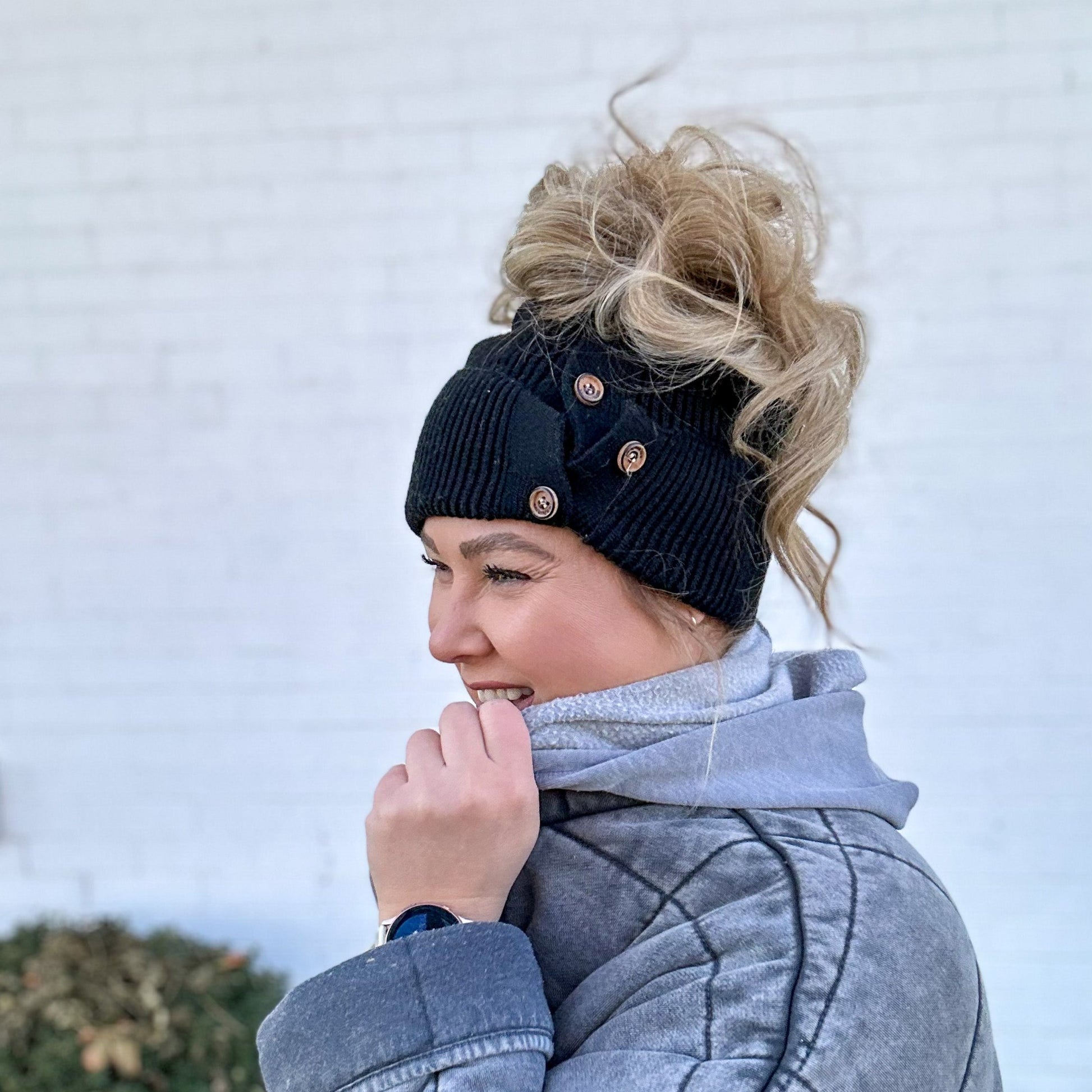 side view of women with large high messy bun wearing Red Sprite Hats black button up beanie