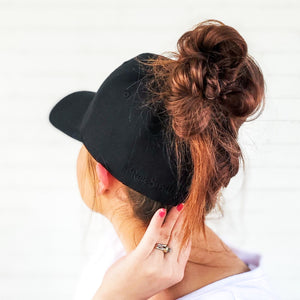 back side of red sprite hats black baseball cap with messy bun and logo showing on hat