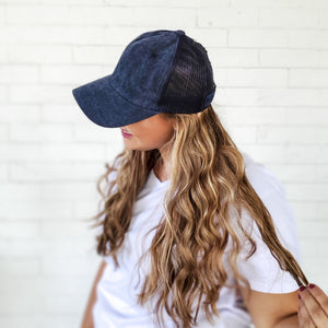 side view of dark blue mesh back messy bun baseball cap with long curly hair red sprite hats